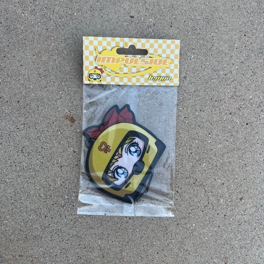 Sailor Venus air freshener hanging from black string. Japanese anime character blonde hair blue eyes wearing yellow helmet with pendent logo and red bow. yellow and white checkered background with yellow y2k impulsive logo and lemon scent label cardboard head card packaging.