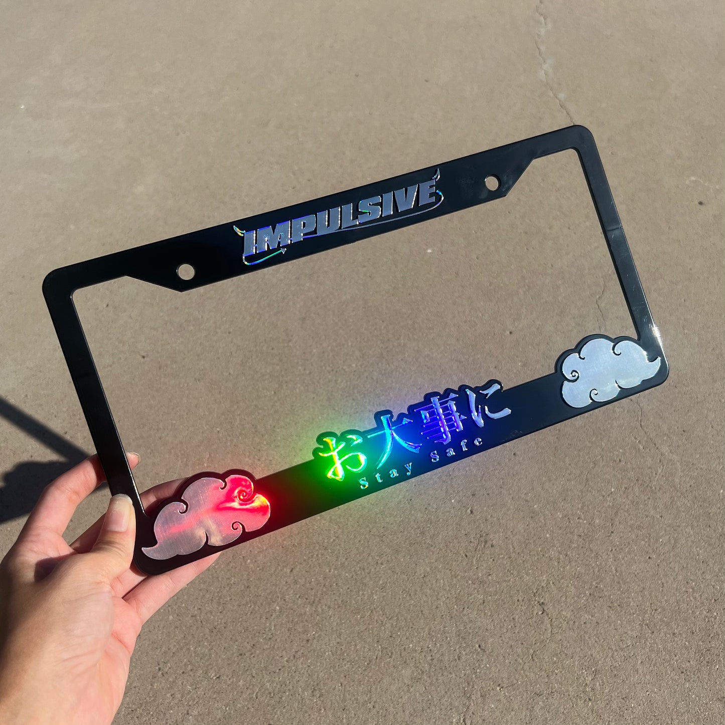 Japanese anime inspired plastic custom License Plate Frame. Top has Impulsive logo and the bottom has japanese characters and english translated to stay safe surrounding with japanese clouds. Asian inspired. Black Frame with rainbow oil slick chrome lettering.