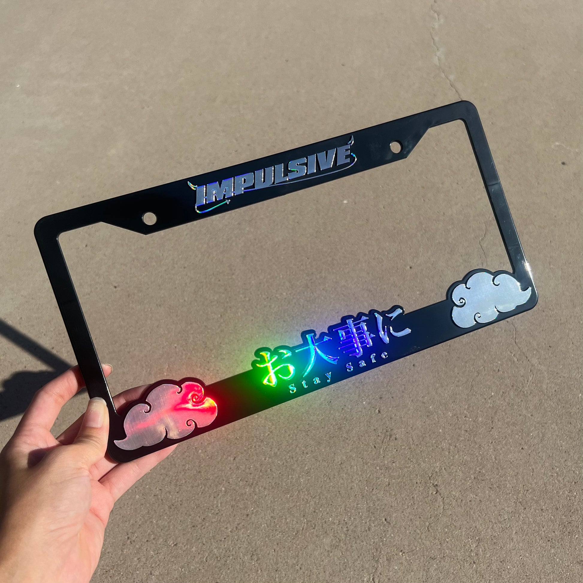 Japanese anime inspired plastic custom License Plate Frame. Top has Impulsive logo and the bottom has japanese characters and english translated to stay safe surrounding with japanese clouds. Asian inspired. Black Frame with rainbow oil slick chrome lettering.