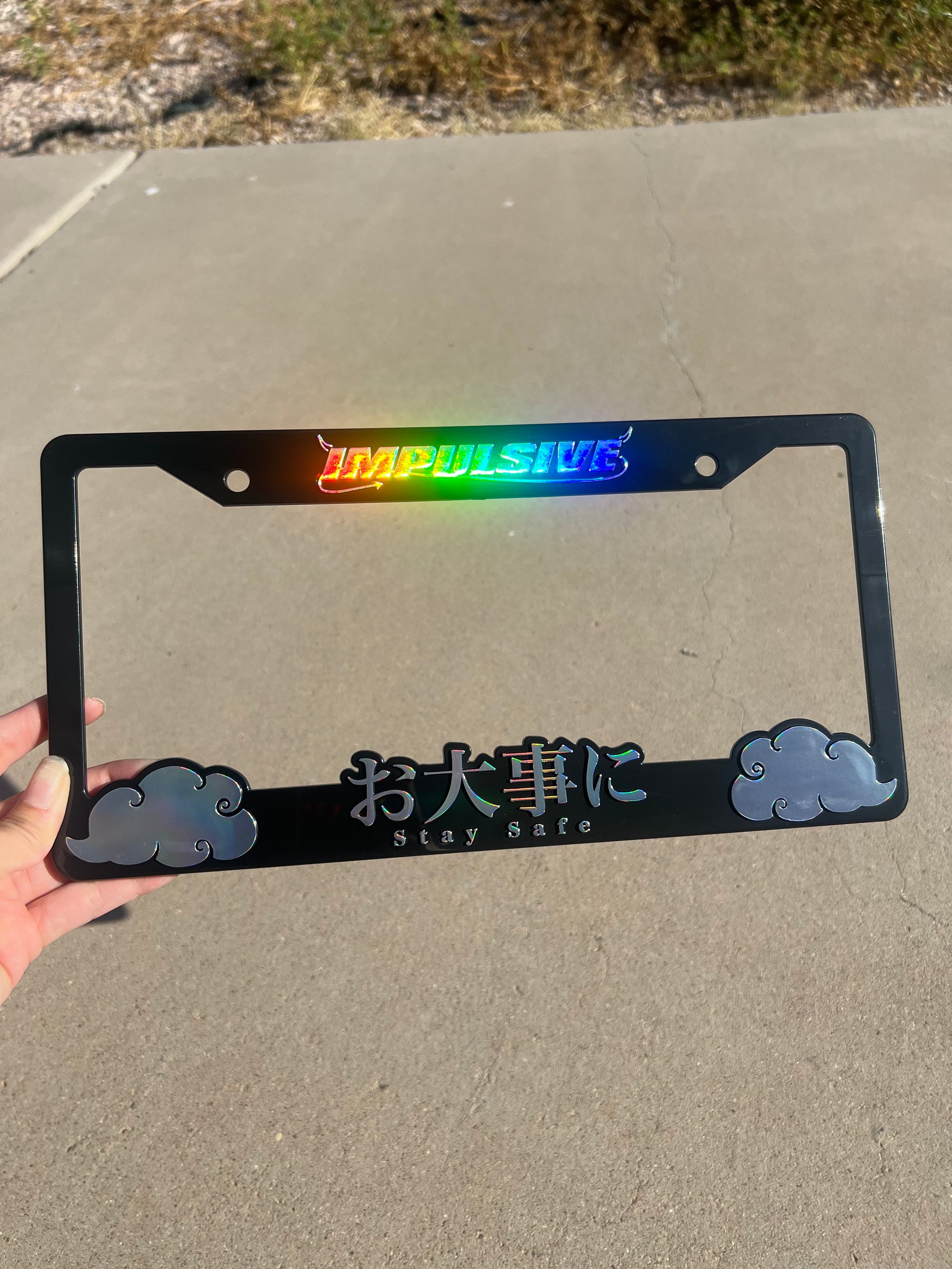 Japanese anime inspired plastic custom License Plate Frame. Top has Impulsive logo and the bottom has japanese characters and english translated to stay safe surrounding with japanese clouds. Asian inspired. Black Frame with rainbow oil slick chrome lettering.