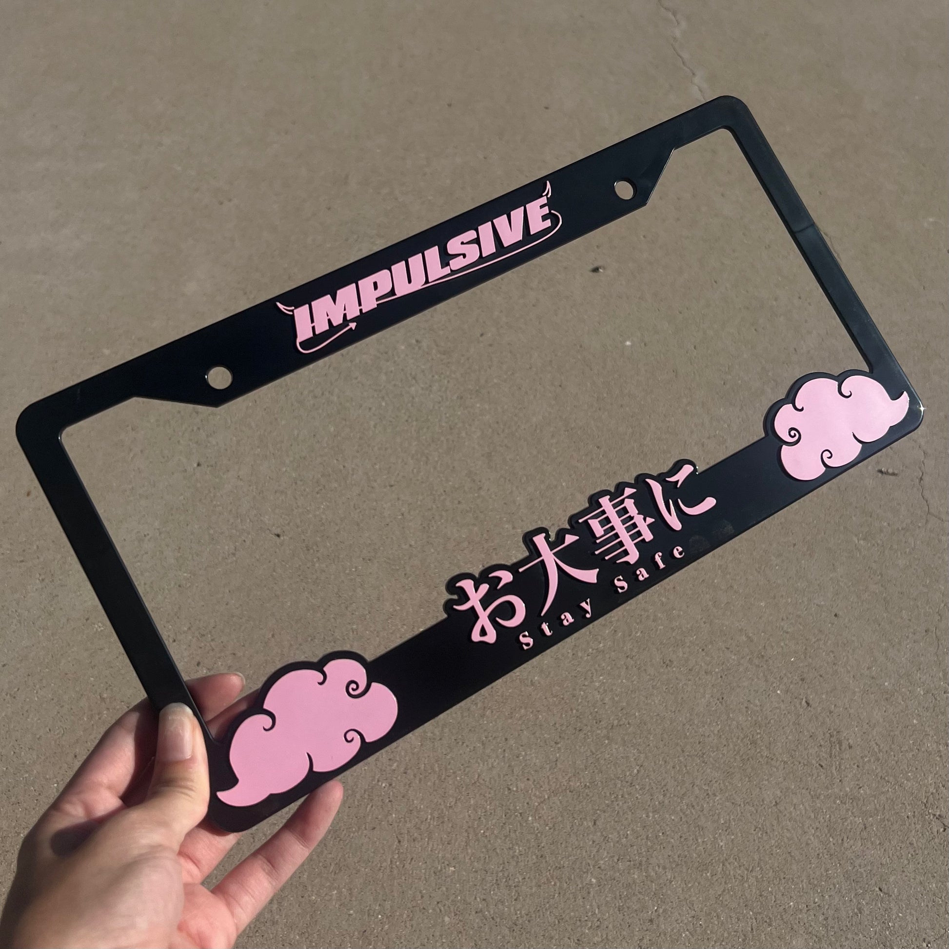 Japanese anime inspired plastic custom License Plate Frame. Top has Impulsive logo and the bottom has japanese characters and english translated to stay safe surrounding with japanese clouds. Asian inspired. Black Frame with Pink lettering.