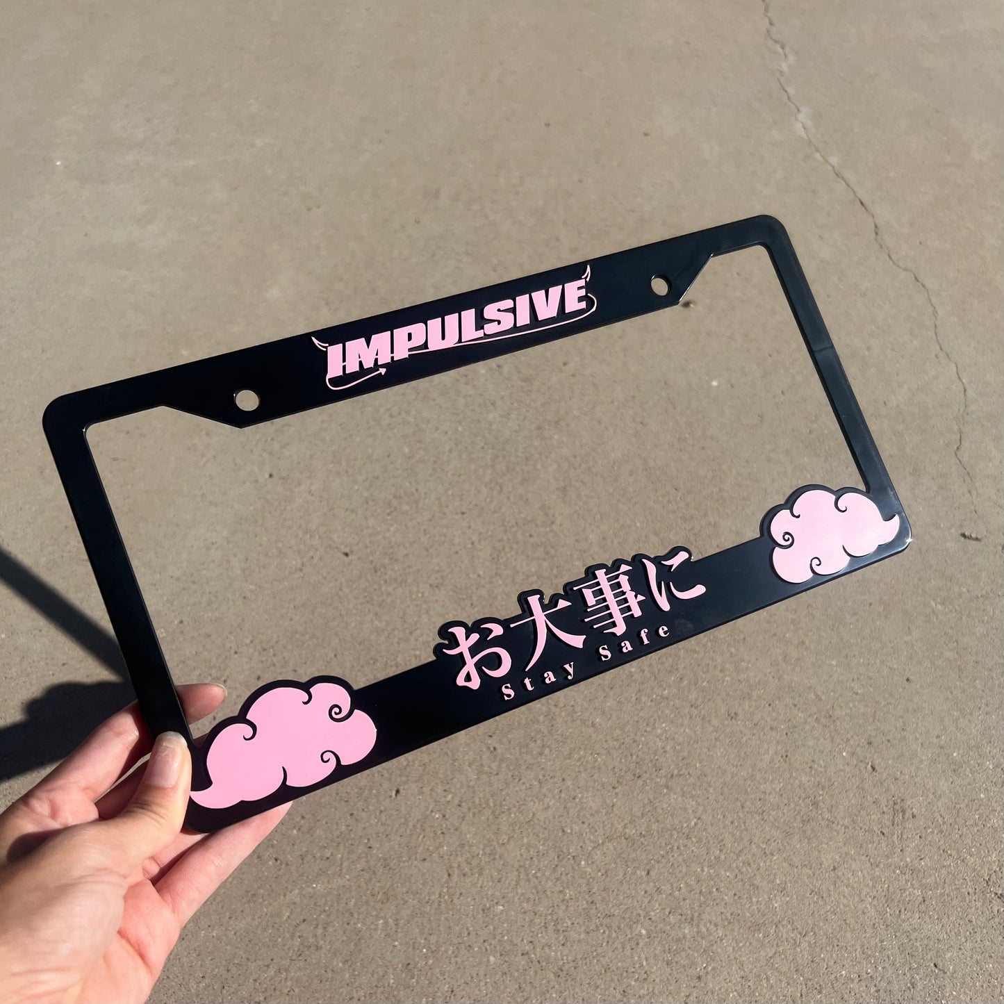 Japanese anime inspired plastic custom License Plate Frame. Top has Impulsive logo and the bottom has japanese characters and english translated to stay safe surrounding with japanese clouds. Asian inspired. Black Frame with Pink lettering.