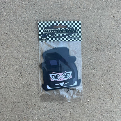 character tuxedo mask air freshener hanging from black string. male japanese anime character wearing black top hat with white glasses and black helmet.  black and white checkered background with black y2k impulsive llc logo and cologne scent label cardboard head card.