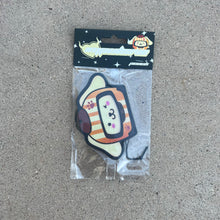 Load image into Gallery viewer, Sanrio Pompompurin Dog Racer Airfreshener hanging from black string. Cream Color dog with orange cream stripe and hat winking with paw prints on helmet. Black Background with stars and impulsive cream color y2k logo with peach label cardboard head card packaging.
