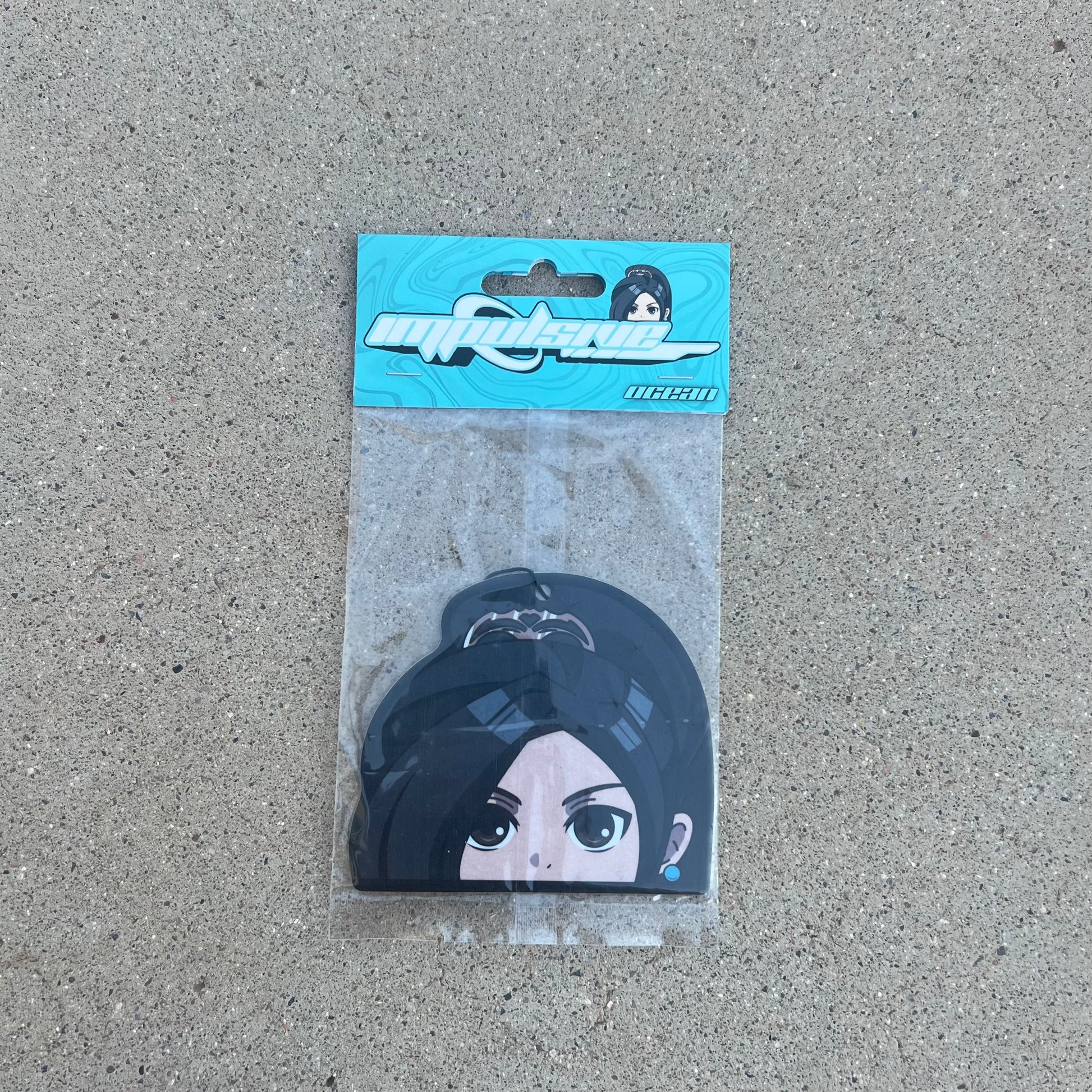 Anime Sage Character air freshener hanging from black string. Asian girl with high pony tail clip, brown eyes and blue pearl earring. Blue swirl background impulsive llc retro y2k logo with ocean scent label cardboard head card packaging.