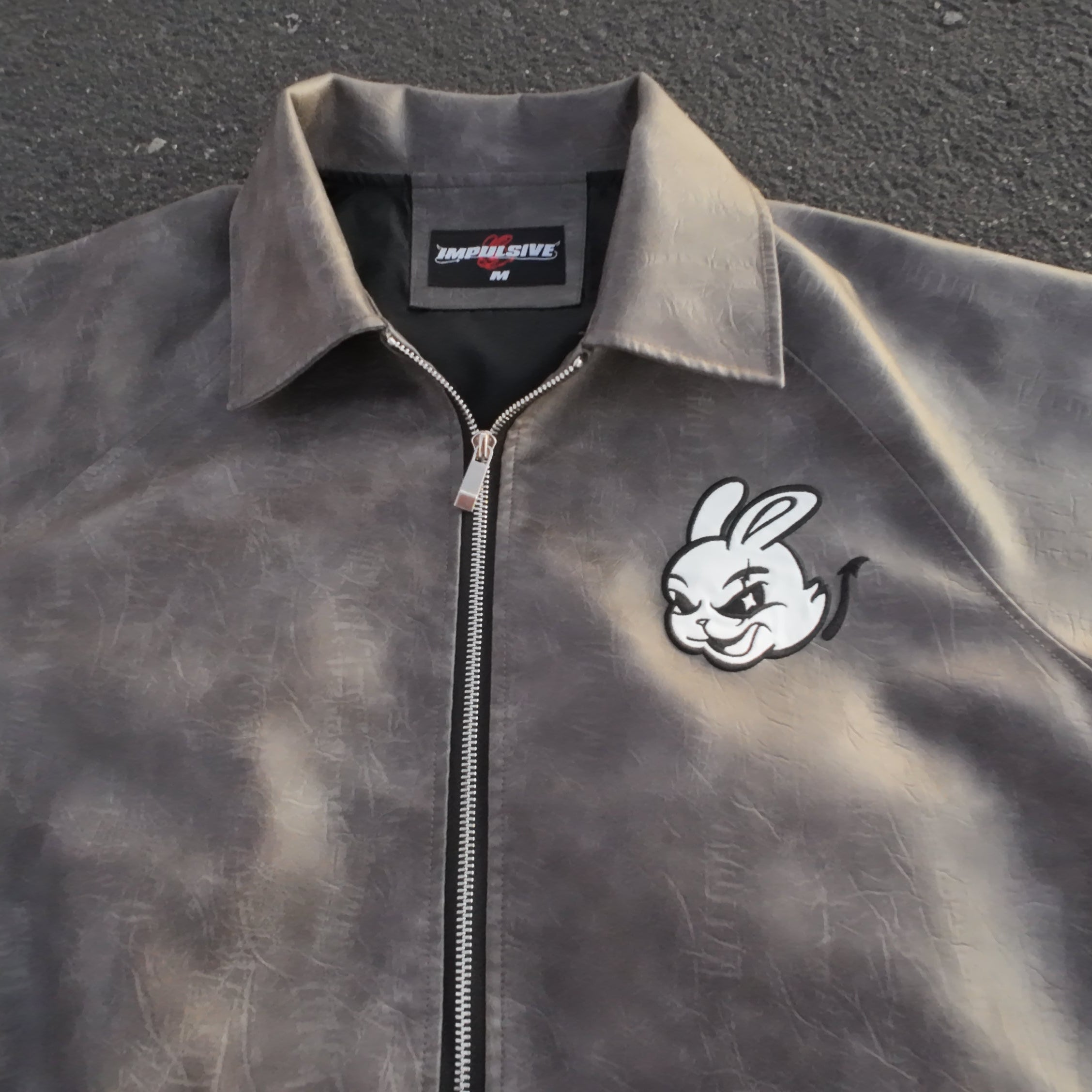 Gray jacket with a logo on a dark surface