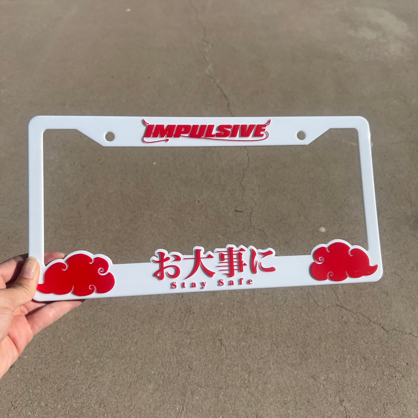 Japanese anime inspired plastic custom License Plate Frame. Top has Impulsive logo and the bottom has japanese characters and english translated to stay safe surrounding with japanese clouds. Asian inspired. White Frame with Red lettering.