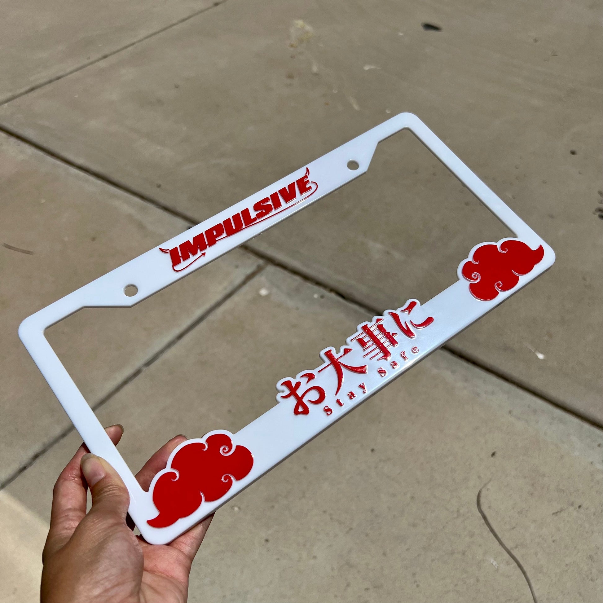 Japanese anime inspired plastic custom License Plate Frame. Top has Impulsive logo and the bottom has japanese characters and english translated to stay safe surrounding with japanese clouds. Asian inspired. White Frame with Red lettering.