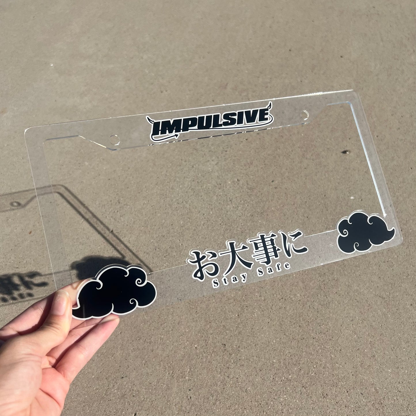 Japanese anime inspired plastic custom License Plate Frame. Top has Impulsive logo and the bottom has japanese characters and english translated to stay safe surrounding with japanese clouds. Asian inspired. Clear Acrylic cut Frame with black and white lettering.