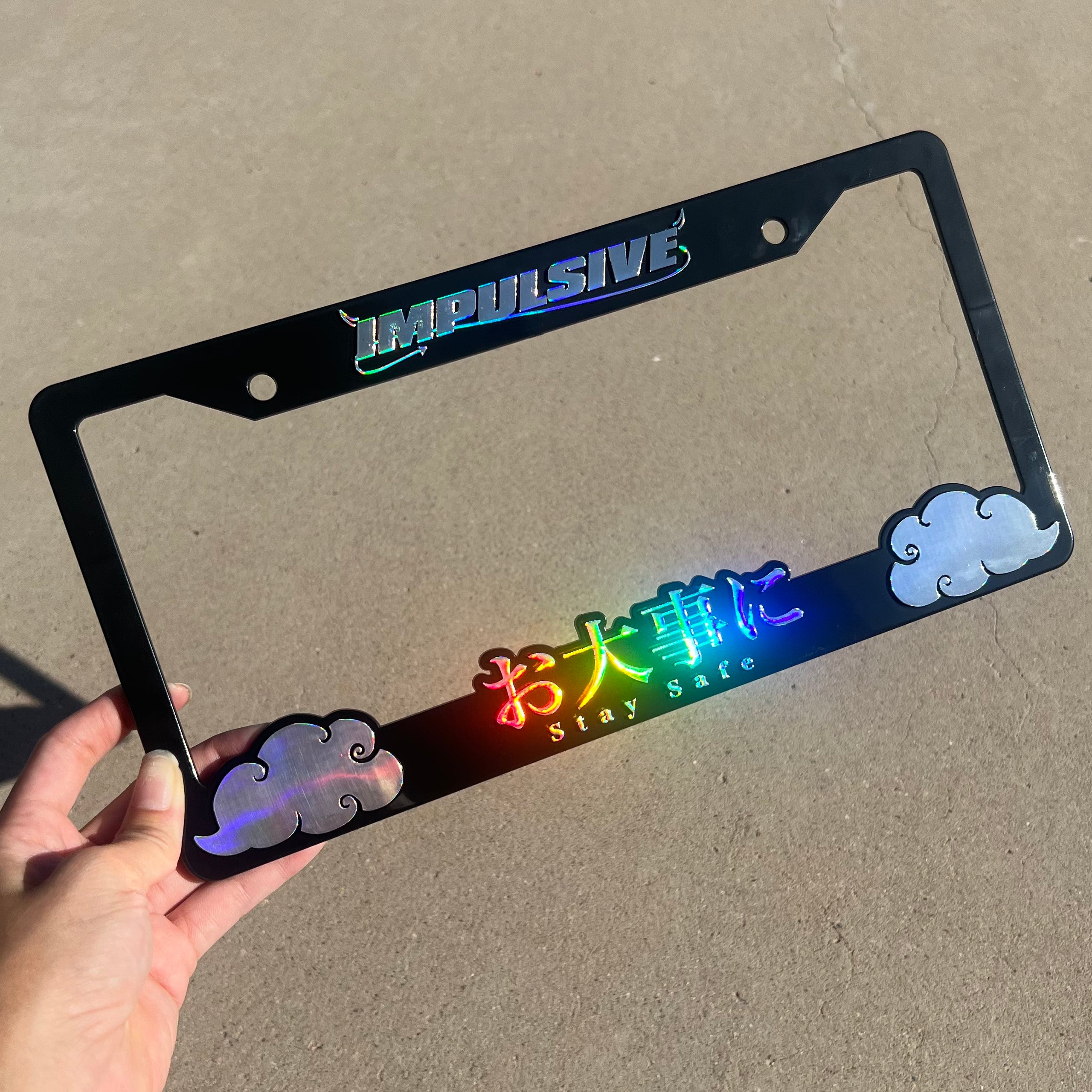 Japanese anime inspired plastic custom License Plate Frame. Top has Impulsive logo and the bottom has japanese characters and english translated to stay safe surrounding with japanese clouds. Asian inspired. Black Frame with rainbow oil slick chrome lettering.