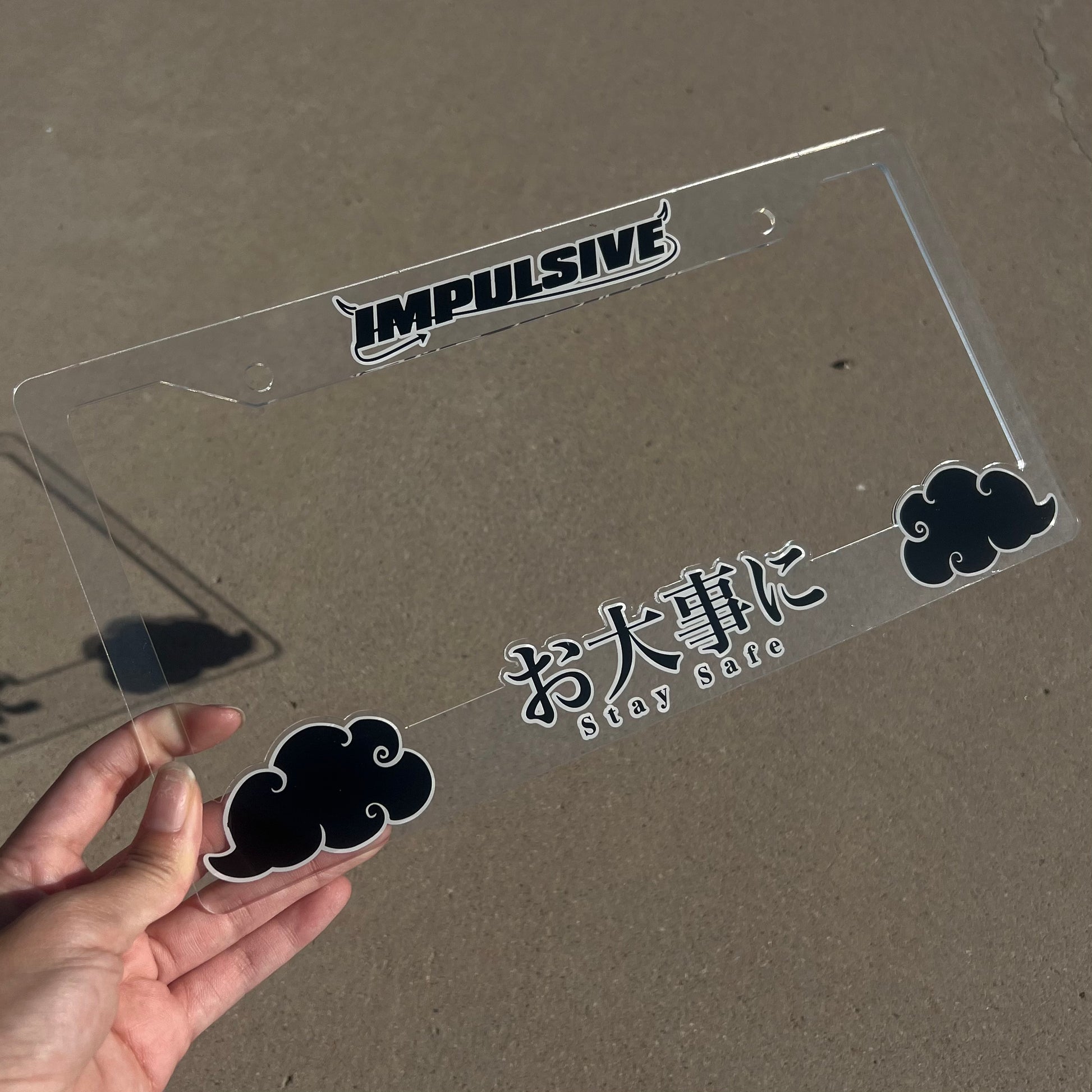 Japanese anime inspired plastic custom License Plate Frame. Top has Impulsive logo and the bottom has japanese characters and english translated to stay safe surrounding with japanese clouds. Asian inspired. Clear Acrylic cut Frame with black and white lettering.