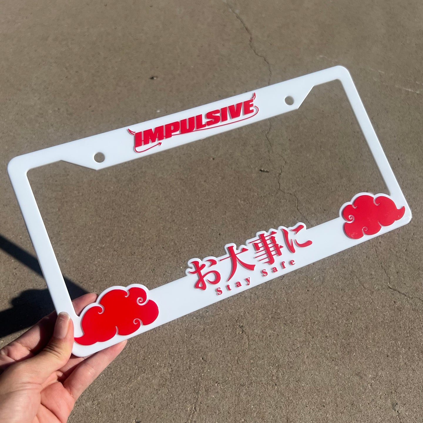 Japanese anime inspired plastic custom License Plate Frame. Top has Impulsive logo and the bottom has japanese characters and english translated to stay safe surrounding with japanese clouds. Asian inspired. White Frame with Red lettering.