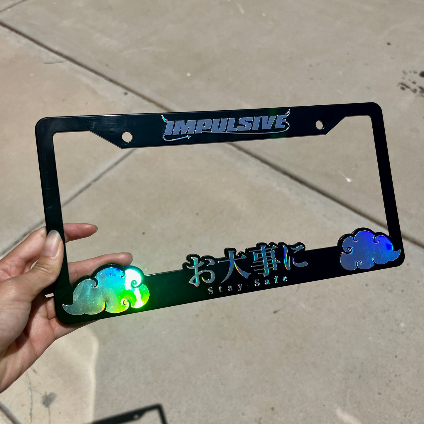 Japanese anime inspired plastic custom License Plate Frame. Top has Impulsive logo and the bottom has japanese characters and english translated to stay safe surrounding with japanese clouds. Asian inspired. Black Frame with chrome rainbow oilslick lettering.