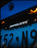Japanese anime inspired plastic custom License Plate Frame. Top has Impulsive logo and the bottom has japanese characters and english translated to stay safe surrounding with japanese clouds. Asian inspired. Black Frame with white lettering.